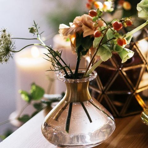 Zdjęcie przedstawiające: Świecznik geometryczny, świecznik mosiężny, dekoracja kwiatowa i wazonik ze złotą szyjką